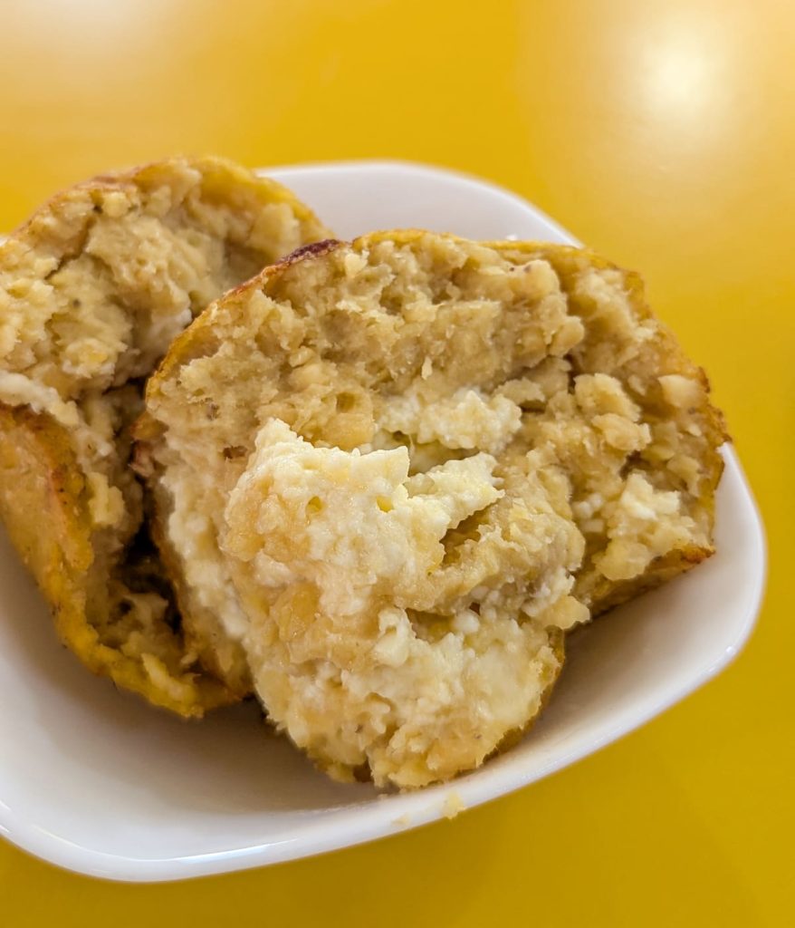 Close-up of a mashed green plantain bolón stuffed with cheese, broken open to show its dense, hearty texture. Bolón is a beloved breakfast item and street food in Ecuador.